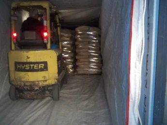 yellow forklift loading pallets of bags into a container